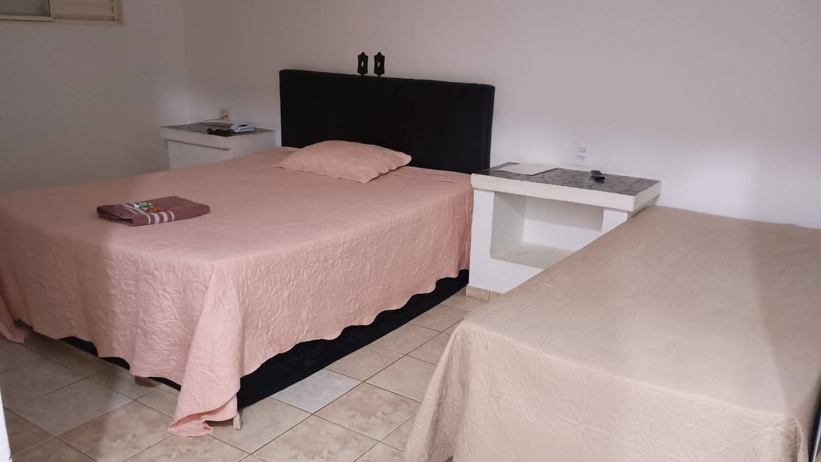 Quarto da Pousada Recanto com cama de casal, colcha floral e toalhas organizadas